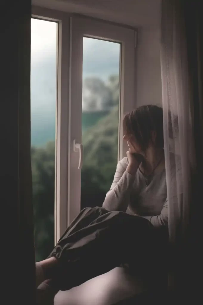 mujer pensativa mirando por la ventana durante crisis de ansiedad
